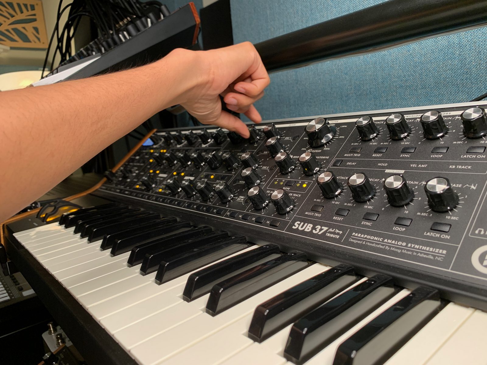 A hand adjusting knobs on a Moog Subsequent 37 synthesizer